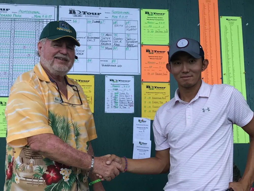 米ミニツアー優勝時の写真。リーダーボードの前で握手するリオコーチ